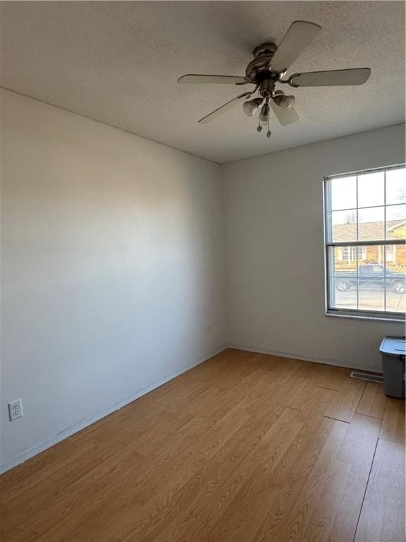 unfurnished room featuring a ceiling fan, light wood-type flooring, and a textured ceiling