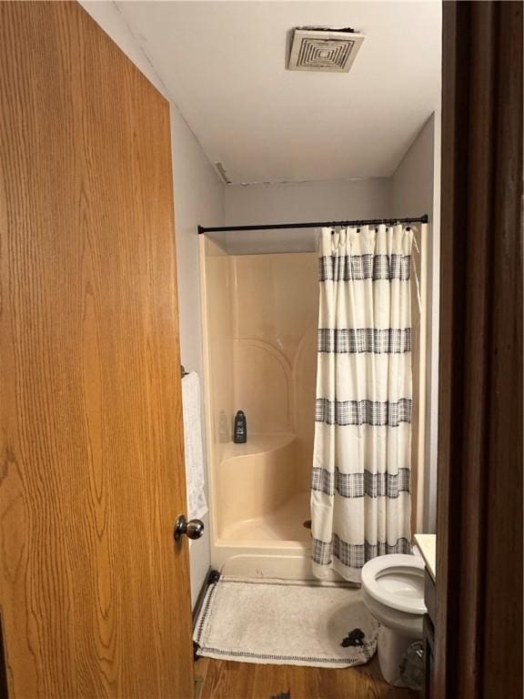 bathroom featuring toilet, a shower with shower curtain, wood finished floors, and visible vents