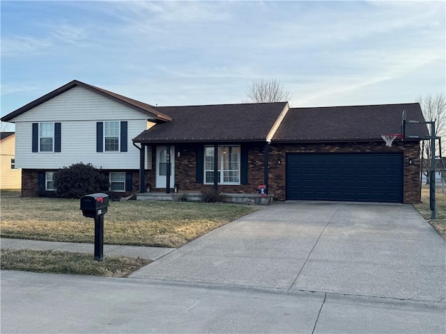 tri-level home featuring a garage, driveway, brick siding, and a front yard