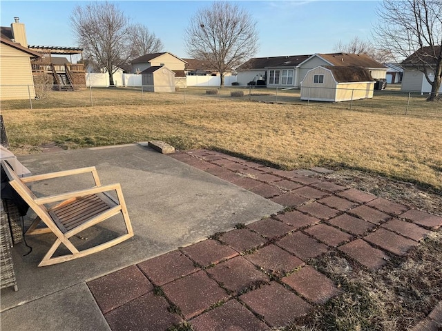 view of yard with a patio, a residential view, an outbuilding, a storage unit, and fence