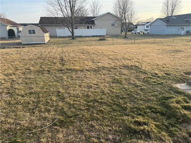 view of yard featuring a storage shed, an outdoor structure, fence, and a residential view