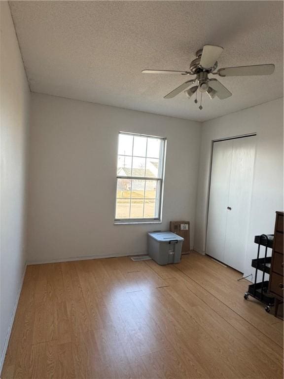 unfurnished bedroom featuring light wood finished floors, ceiling fan, a closet, and a textured ceiling