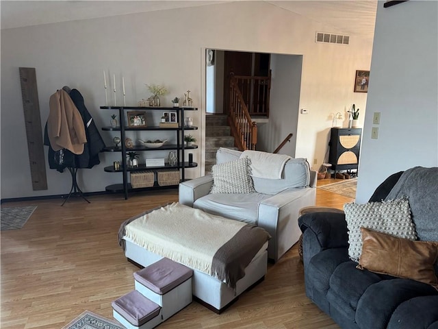 living room with stairway, visible vents, vaulted ceiling, and wood finished floors