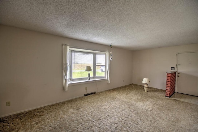 empty room featuring visible vents, light carpet, and a textured ceiling