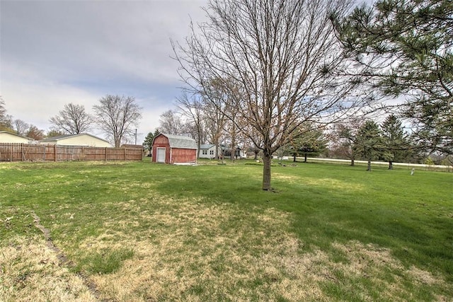 view of yard featuring an outbuilding, a detached garage, fence, and a barn