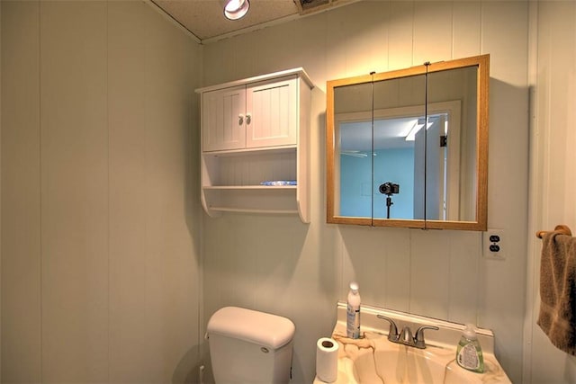 bathroom with a sink, toilet, and a decorative wall
