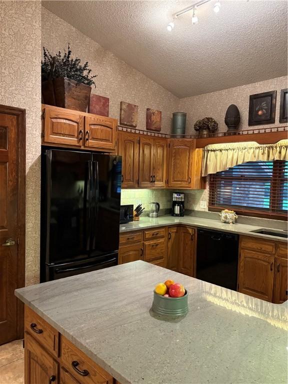 2236 Seneca Dr, Charleston, IL 61920 - kitchen featuring black appliances, vaulted ceiling, brown cabinetry, a textured ceiling, and a textured wall