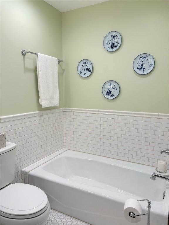 2236 Seneca Dr, Charleston, IL 61920 - bathroom with wainscoting, tile patterned flooring, a bath, toilet, and tile walls
