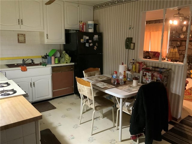 603 W English St, Danville, IL 61832 - kitchen featuring white cabinetry, light flooring, freestanding refrigerator, a sink, and wallpapered walls