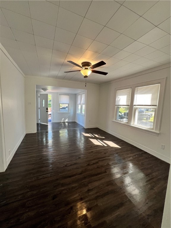 unfurnished living room featuring ornamental molding, ceiling fan, and dark wood-type flooring