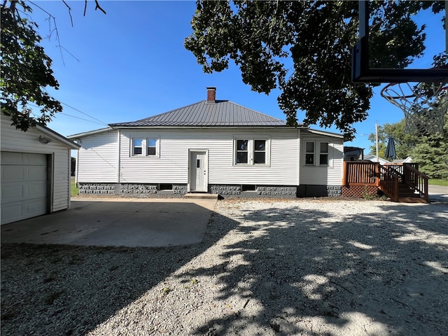 rear view of house featuring a garage, an outdoor structure, and a wooden deck