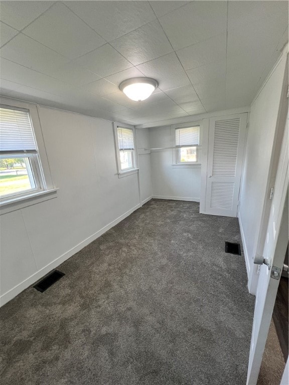 basement with a wealth of natural light and dark carpet