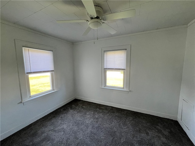 spare room featuring dark carpet, ornamental molding, and a wealth of natural light