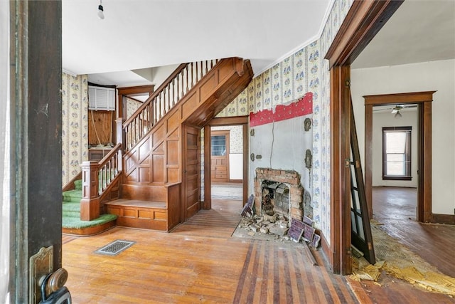 426 W Madison St, Paris, IL 61944 - stairs with wood finished floors, a fireplace with flush hearth, wallpapered walls, and ceiling fan