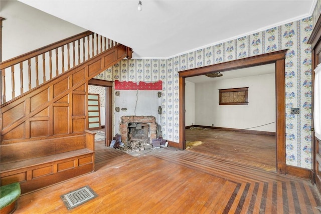 426 W Madison St, Paris, IL 61944 - unfurnished living room with wallpapered walls, baseboards, wood finished floors, a stone fireplace, and stairs