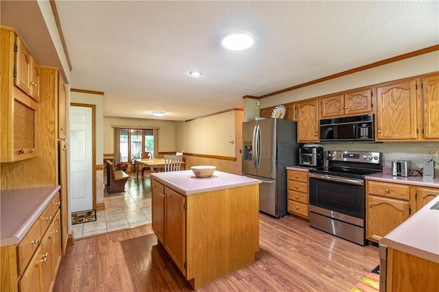 5353 E Reas Bridge Rd, Decatur, IL 62521 - kitchen featuring appliances with stainless steel finishes, a kitchen island, ornamental molding, a wainscoted wall, and light wood-type flooring