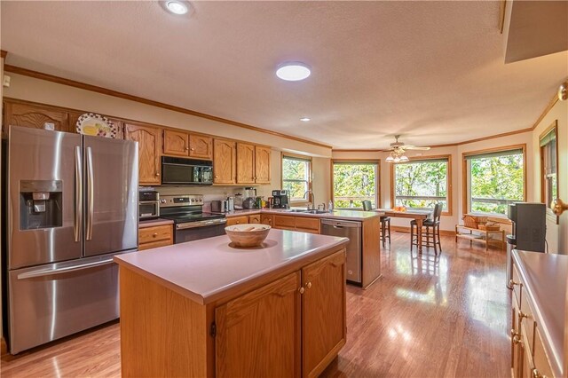 5353 E Reas Bridge Rd, Decatur, IL 62521 - kitchen with stainless steel appliances, a sink, crown molding, light wood-style flooring, and a peninsula