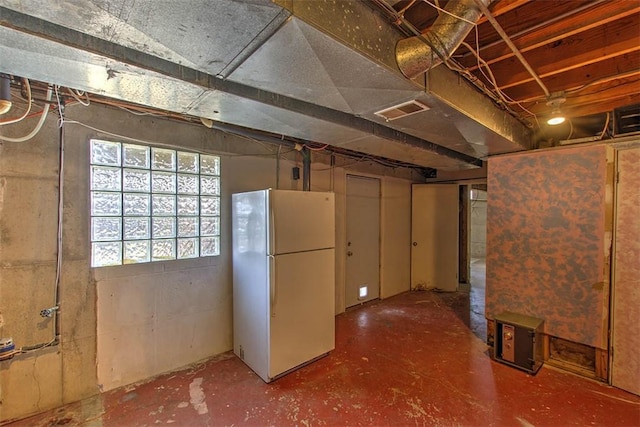 below grade area featuring visible vents and freestanding refrigerator