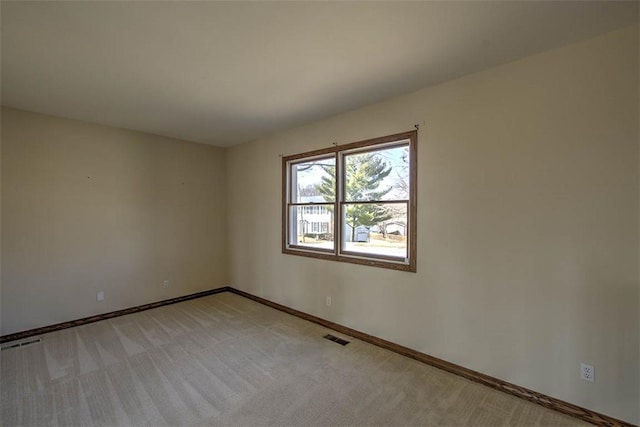 spare room featuring baseboards, visible vents, and light colored carpet