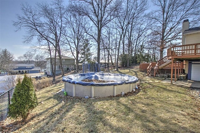 view of yard with a covered pool, fence, stairway, and a wooden deck