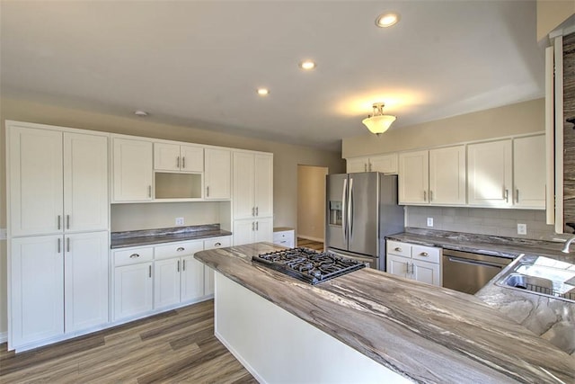 kitchen with white cabinetry, stainless steel appliances, a sink, and wood finished floors