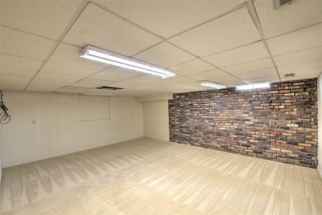 finished basement with brick wall, a drop ceiling, carpet flooring, and visible vents