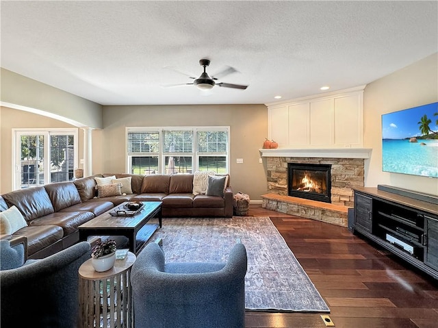 living area with dark wood-style flooring, a fireplace, plenty of natural light, and a textured ceiling