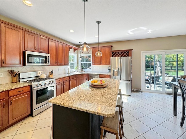 kitchen with tasteful backsplash, a breakfast bar, stainless steel appliances, pendant lighting, and light tile patterned flooring