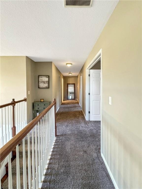 corridor with a textured ceiling, an upstairs landing, visible vents, baseboards, and carpet