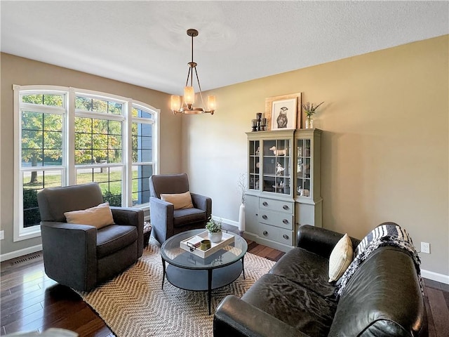 living room featuring a chandelier, visible vents, baseboards, and wood finished floors