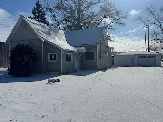 view of front facade featuring a detached garage, metal roof, and an outbuilding