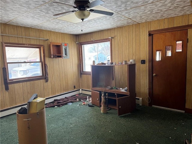 interior space with a baseboard radiator, wooden walls, and ceiling fan