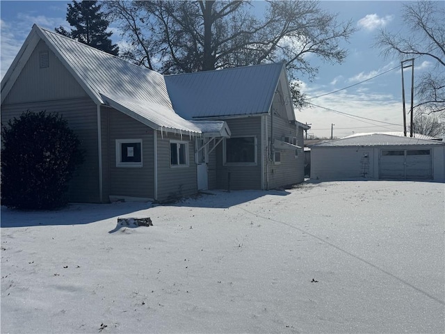 back of property featuring a garage, metal roof, and an outdoor structure