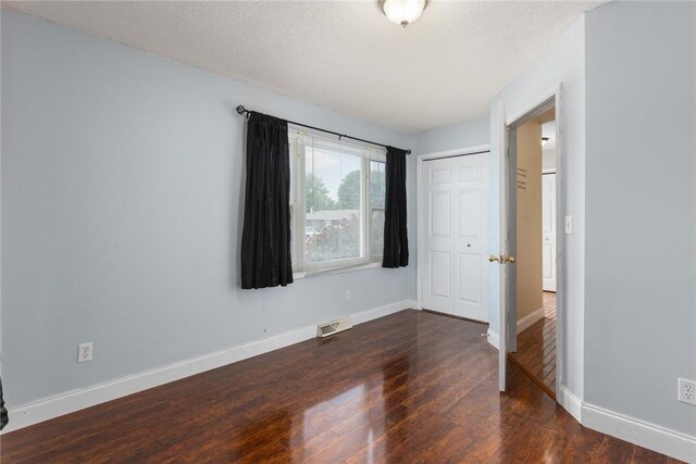 510 N Merchant St, Effingham, IL 62401 - unfurnished bedroom featuring dark wood-style flooring, baseboards, a closet, and a textured ceiling