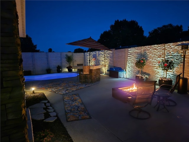 1003 Flame Ave, Effingham, IL 62401 - patio at twilight featuring an outdoor fire pit, a fenced backyard, and a patio