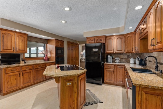 1003 Flame Ave, Effingham, IL 62401 - kitchen with black appliances, brown cabinetry, a textured ceiling, a kitchen island, and light stone countertops