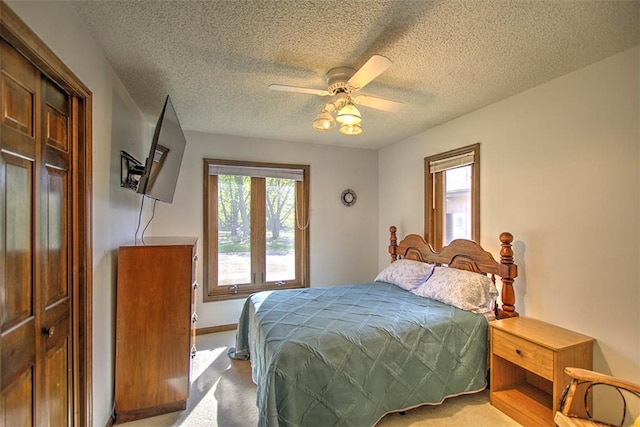 bedroom with ceiling fan, baseboards, multiple windows, and a textured ceiling
