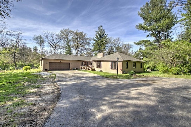 single story home featuring driveway, a chimney, and a garage