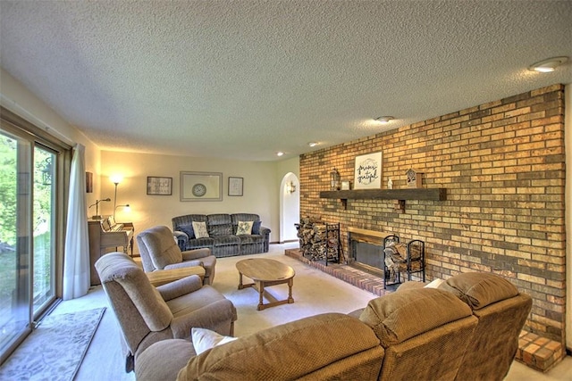 living room with a fireplace, a textured ceiling, light colored carpet, and brick wall