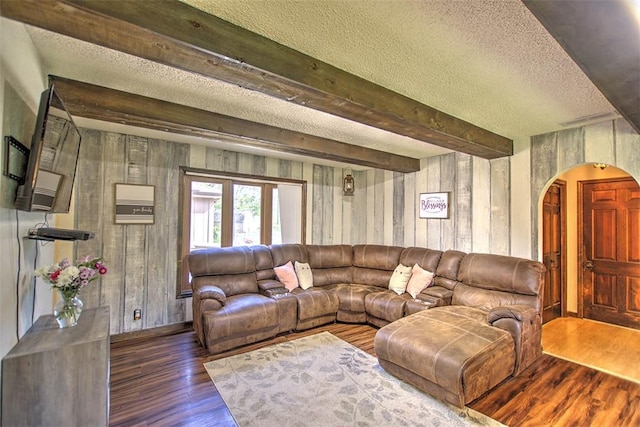 living area featuring arched walkways, wooden walls, wood finished floors, and a textured ceiling