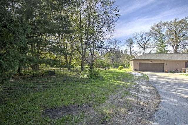view of yard featuring a garage and aphalt driveway