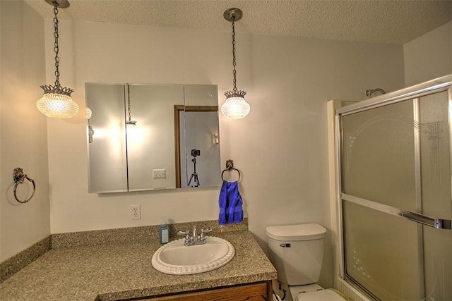 full bathroom with toilet, vanity, a textured ceiling, and an enclosed shower