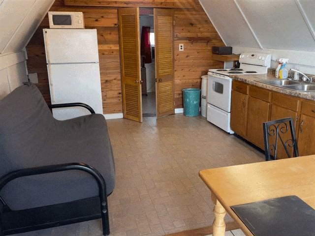 kitchen with lofted ceiling, sink, wooden walls, and white appliances