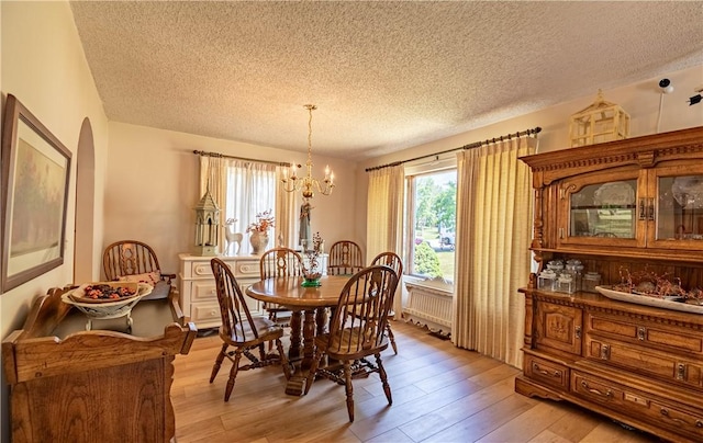 1059 Columbia Dr, Decatur, IL 62522 - dining room featuring a textured ceiling, a chandelier, arched walkways, and light wood-style flooring