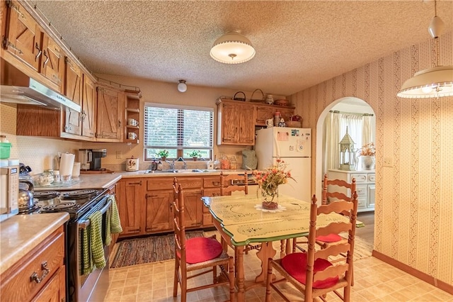 1059 Columbia Dr, Decatur, IL 62522 - kitchen with wallpapered walls, freestanding refrigerator, electric stove, arched walkways, and plenty of natural light