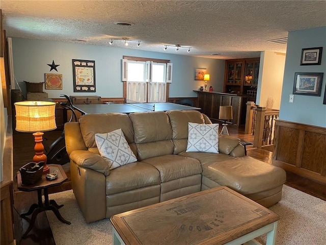 living room featuring a textured ceiling, a dry bar, rail lighting, and visible vents