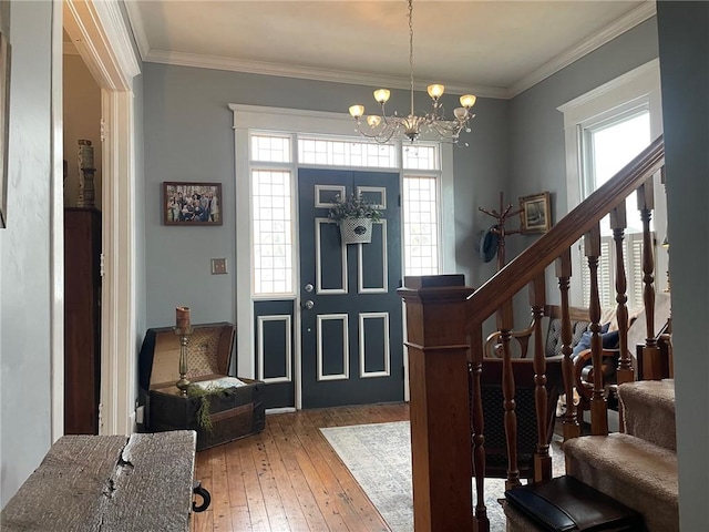 entrance foyer with crown molding, an inviting chandelier, wood-type flooring, and stairway