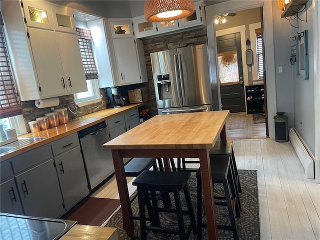 kitchen with wooden counters, backsplash, light wood-style flooring, and appliances with stainless steel finishes