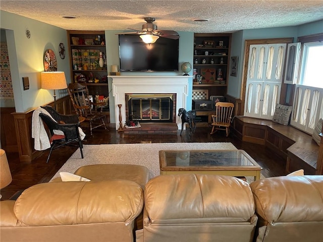 living room with a textured ceiling, ceiling fan, and built in shelves