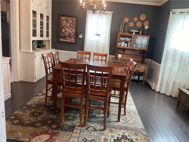 dining area featuring dark wood-type flooring, crown molding, and an inviting chandelier